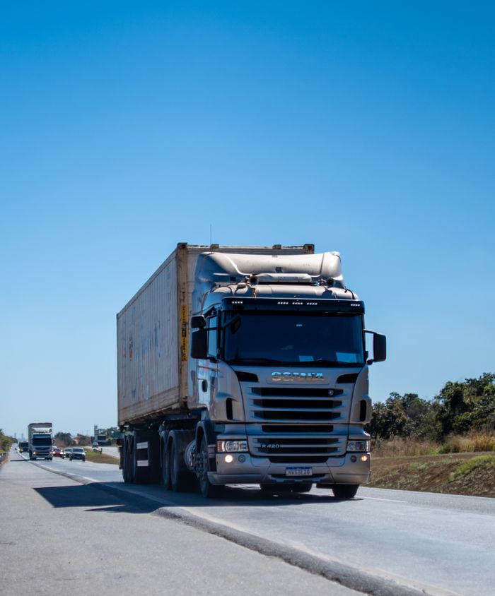 about-us-02 A large cargo truck travels on a highway in Brazil under clear blue skies.